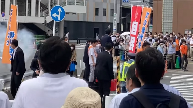 Instante del primer disparo contra Shinzo Abe. A la izquierda de la imagen nótese el humo que sale de la escopeta. (Kansai TV)