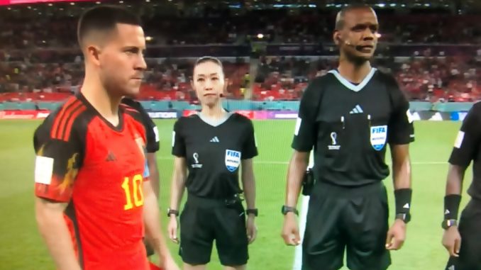 Yoshimi Yamashita, con rostro serio, mientras espera el sorteo del campo. Frente a ella Hazard de Bélgica