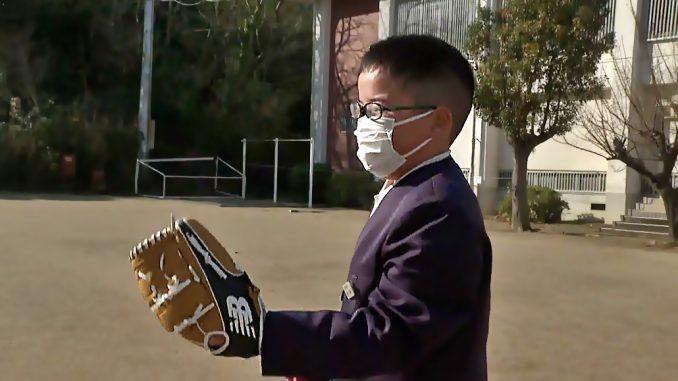 Niño de Ehime prueba el guante donado por Ohtani. (Ehime News)