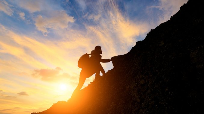 Man,Climbing,Mountain,At,Sunrise,conceptual,Scene